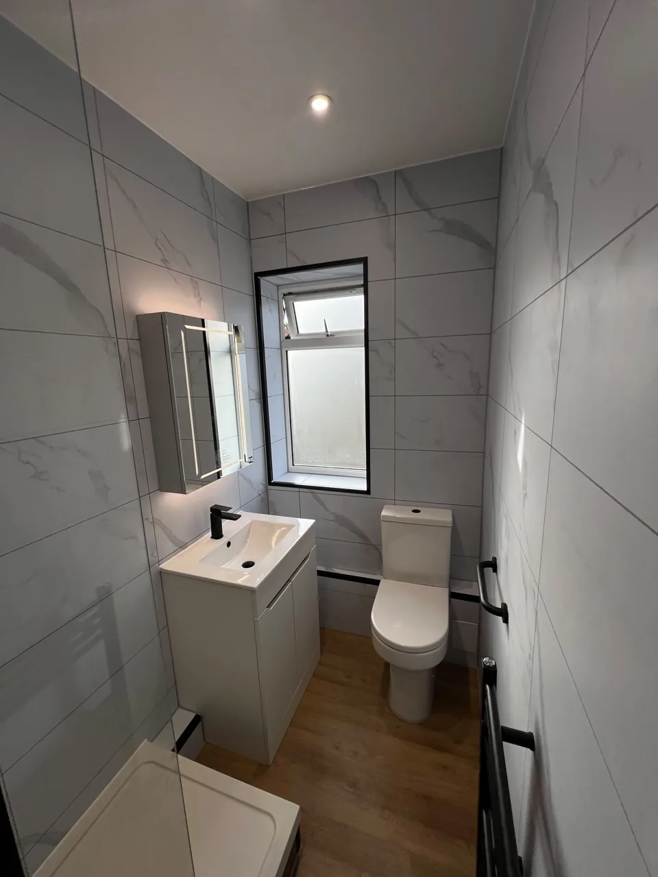Narrow shower room with black fittings and wood-effect floor