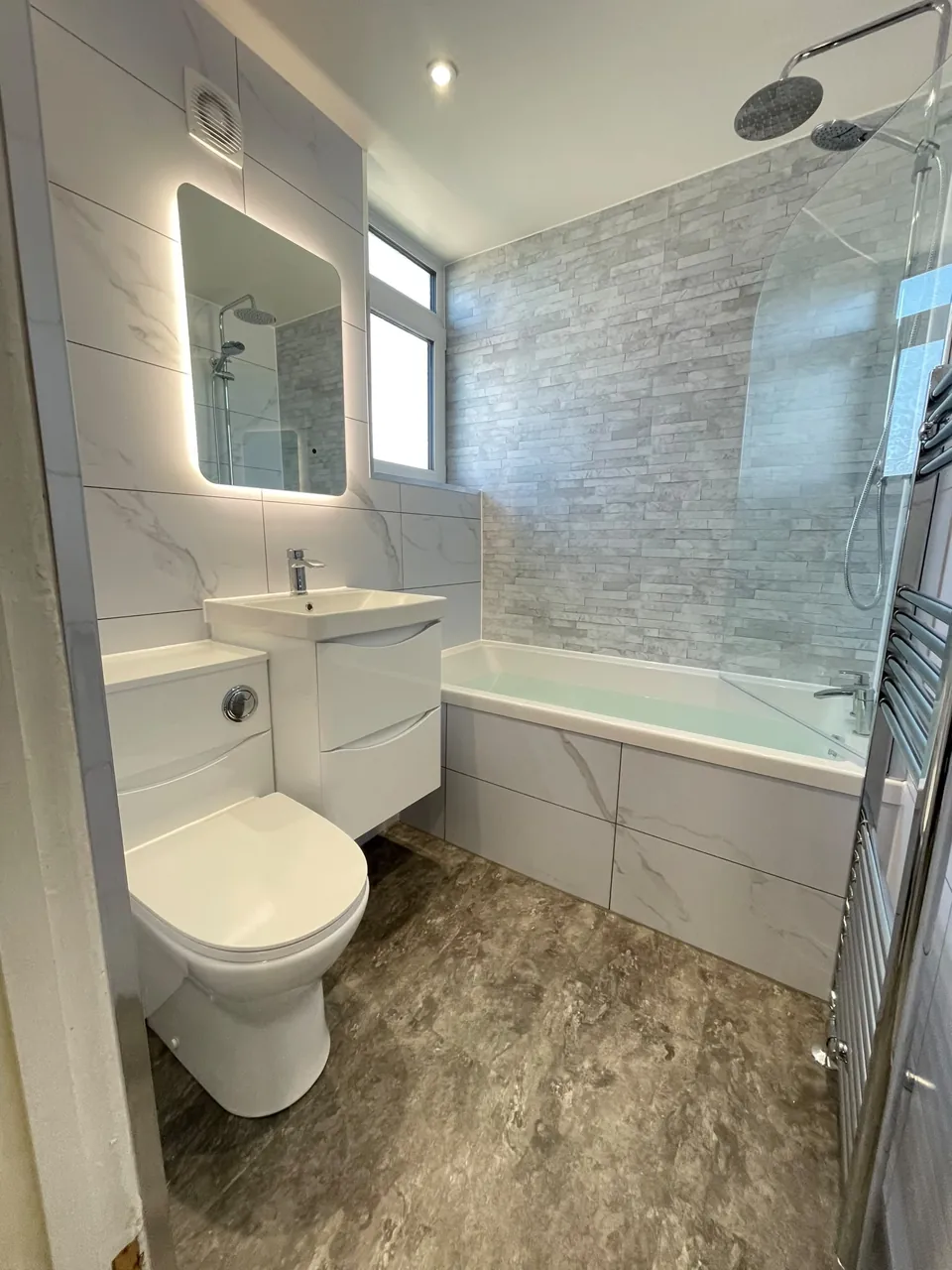 White fitted bath and vanity with marble-effect walls