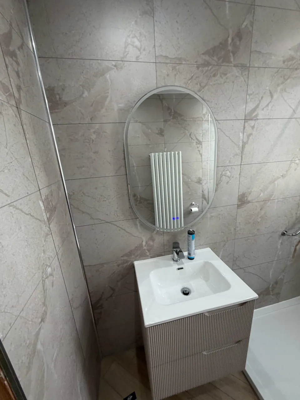 White basin and vanity beneath a rounded mirror